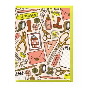 May include: A greeting card with a light pink background featuring a repeating pattern of stationery items including scissors, pens, a highlighter labeled Highlighter, an eraser labeled Eraser, ink, stamps, envelopes, washi tape, and a slice of cake.