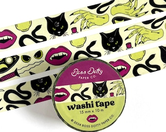 May include: A roll of washi tape with a black cat, snake, hand, and lips design on a cream background. The tape is 15 mm wide and 10 m long. The text on the tape reads "Boss Dotty Paper Co. Washi tape 15 mm x 10 m © 2024 BOSS DOTTY PAPER CO."