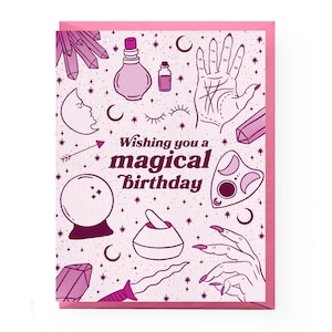 May include: Pink and white greeting card with a magical birthday message and illustrations of crystals, moons, a hand with a palm reading, a potion bottle, a crystal ball, a mortar and pestle, a dagger, and a Ouija board.