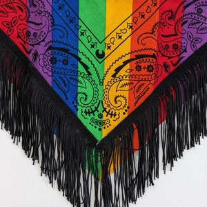 May include: A triangular bandana featuring vertical rainbow stripes in purple, blue, green, yellow, orange, and red. The fabric is decorated with a black paisley print pattern and is finished with long, black fringe trim along the bottom edges.