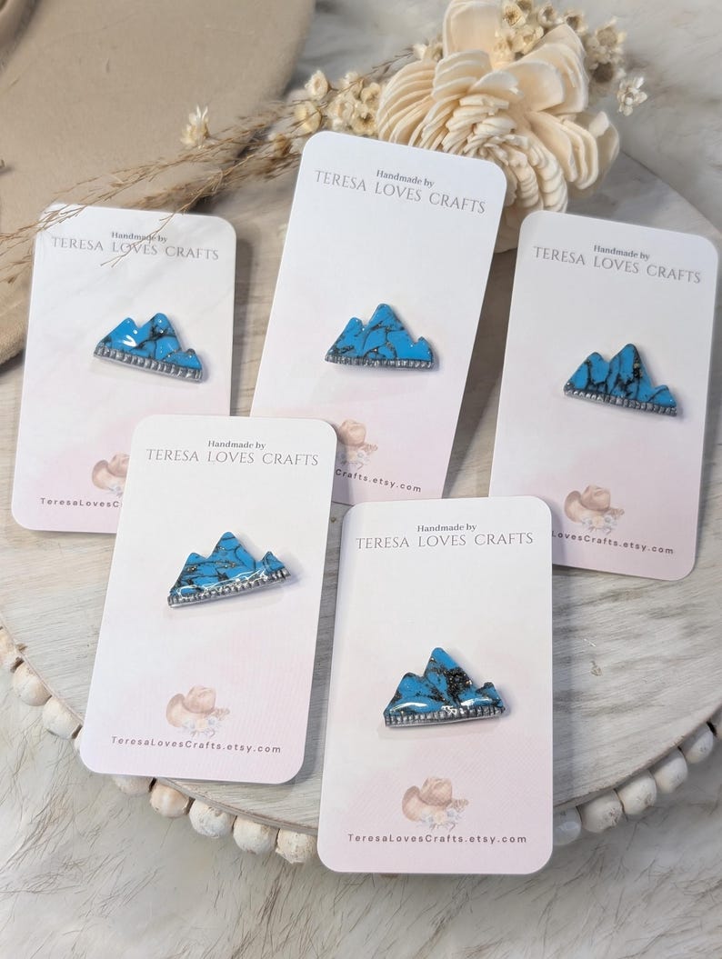 Może przedstawiać: Pięć kartek z turkusowymi wzorami g&oacute;r. Każda kartka zawiera tekst "Handmade by TERESA LOVES CRAFTS" i adres strony internetowej.