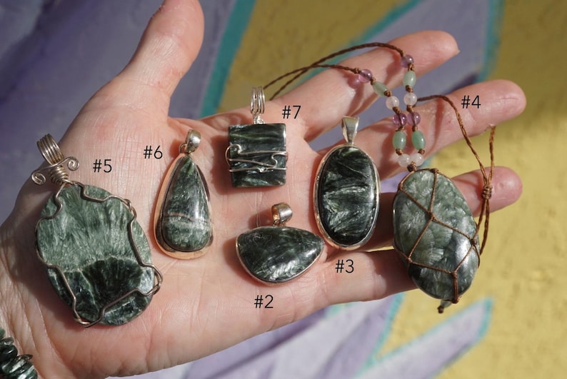 K&ouml;nnte beinhalten: Eine Sammlung von Edelsteinanh&auml;ngern in verschiedenen Formen und Designs. Die Anh&auml;nger sind haupts&auml;chlich gr&uuml;n und grau, mit silbernen oder Drahtakzenten. Einige sind an Kordeln oder Ketten aufgereiht.