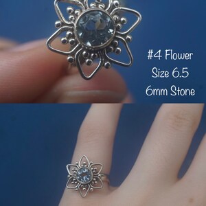 May include: A silver ring with a blue gemstone in the center, shaped like a flower with six points. The ring is size 6.5 and the stone is 6mm. #4 Flower