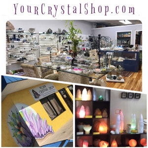 May include: A crystal shop with a yellow exterior and a mural of purple crystals. The shop has a sign that reads "Your Crystal Shop". Inside the shop, there are shelves of crystals, jewelry, and other items. There are also salt lamps on display.