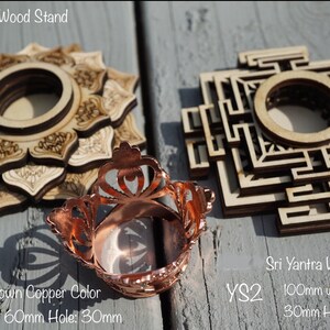May include: Two wooden stands for crystals or other objects. The stand on the left is a lotus design and the stand on the right is a Sri Yantra design. Both stands are 100mm in diameter with a 30mm hole. A copper colored sphere stand is also shown. The sphere stand is 60mm in diameter with a 30mm hole.