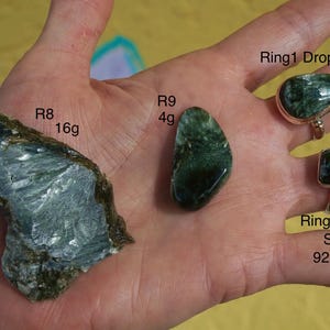 K&ouml;nnte beinhalten: Eine Hand zeigt verschiedene Edelsteine und Ringe. Zwei Ringe sind sichtbar, einer tropfenf&ouml;rmig und einer quadratisch, beide mit gr&uuml;nen Steinen und 925er Silberfassungen. Die Ringe haben die Gr&ouml;&szlig;e 8 und 9. Zwei rohe Edelsteine sind ebenfalls abgebildet, einer wiegt 16g und der andere 4g.
