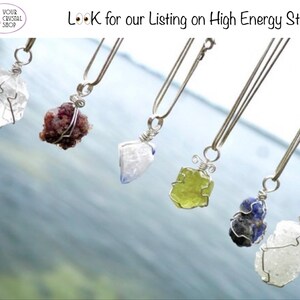 May include: Six silver necklaces with different colored crystal pendants. The crystals are wrapped in silver wire. The necklaces are hanging against a blue and white background.  "Look for our listing on High Energy Stones"