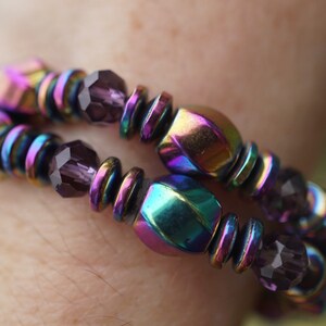 Puede incluir: Un brazalete de m&uacute;ltiples hilos con cuentas hexagonales iridiscentes y facetadas y cuentas de vidrio morado oscuro.