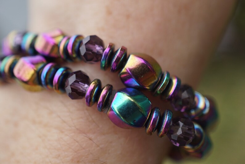 Puede incluir: Un brazalete de m&uacute;ltiples hilos con cuentas hexagonales iridiscentes y facetadas y cuentas de vidrio morado oscuro.