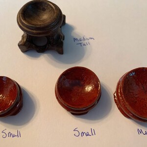 May include: Four wooden display stands for crystals or other small objects. The stands are in different sizes: extra small, small, medium, and medium tall. The stands are made of dark wood and have a smooth, polished finish.