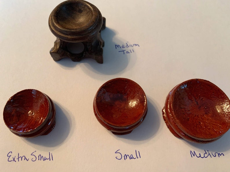 May include: Four wooden display stands for crystals or other small objects. The stands are in different sizes: extra small, small, medium, and medium tall. The stands are made of dark wood and have a smooth, polished finish.