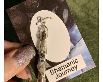May include: A silver pendant with a clear glass tube filled with small stones and crystals. The pendant is on a white card with the text "Shamanic Journey" and a price tag of $40.