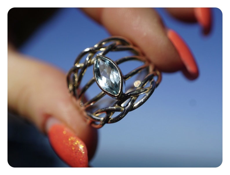 May include: A silver ring with a light blue gemstone set in a woven band.