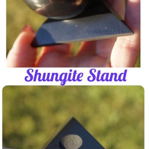 May include: A black shungite pyramid stand with a round indentation on top. The stand is made of polished black stone and has a smooth, glossy finish.  Shungite Stand.