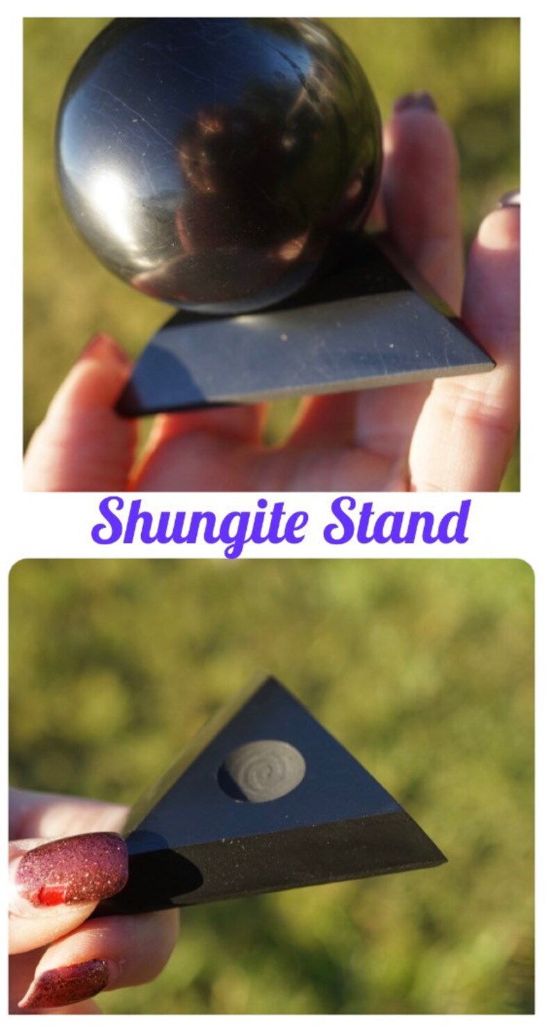 May include: A black shungite pyramid stand with a round indentation on top. The stand is made of polished black stone and has a smooth, glossy finish.  Shungite Stand.