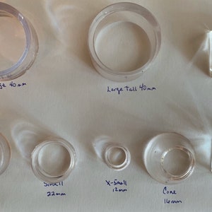 May include: Assortment of clear glass rings and cubes in various sizes. The rings are labeled "Large 40mm", "Large Tall 40mm", "Medium 30mm", "Small 22mm", "X-Small 12mm", and "Cone 16mm". The cubes are labeled "Glass Square 30mm" and "Glass Cube 25mm".