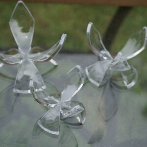 May include: Three clear acrylic egg display stands of different sizes. The stands are shaped like a flower with four petals.