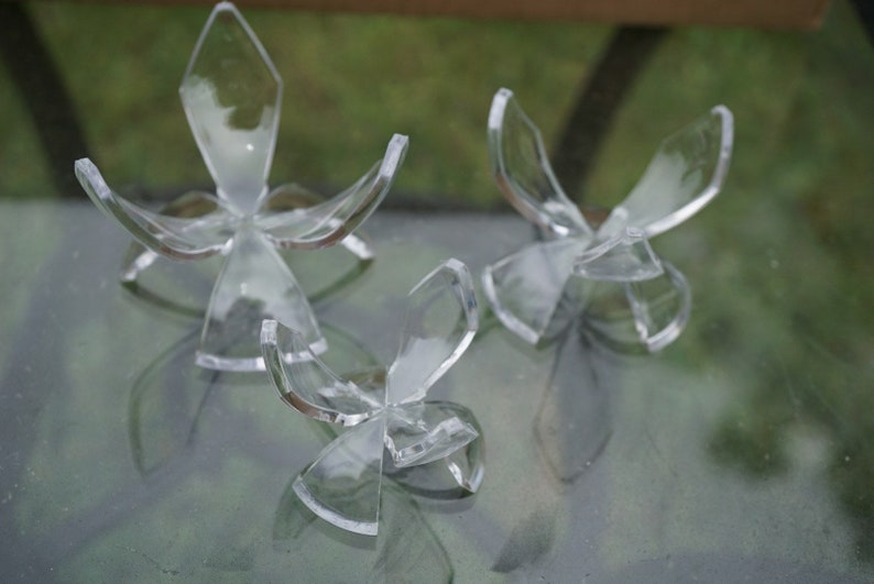 May include: Three clear acrylic egg display stands of different sizes. The stands are shaped like a flower with four petals.