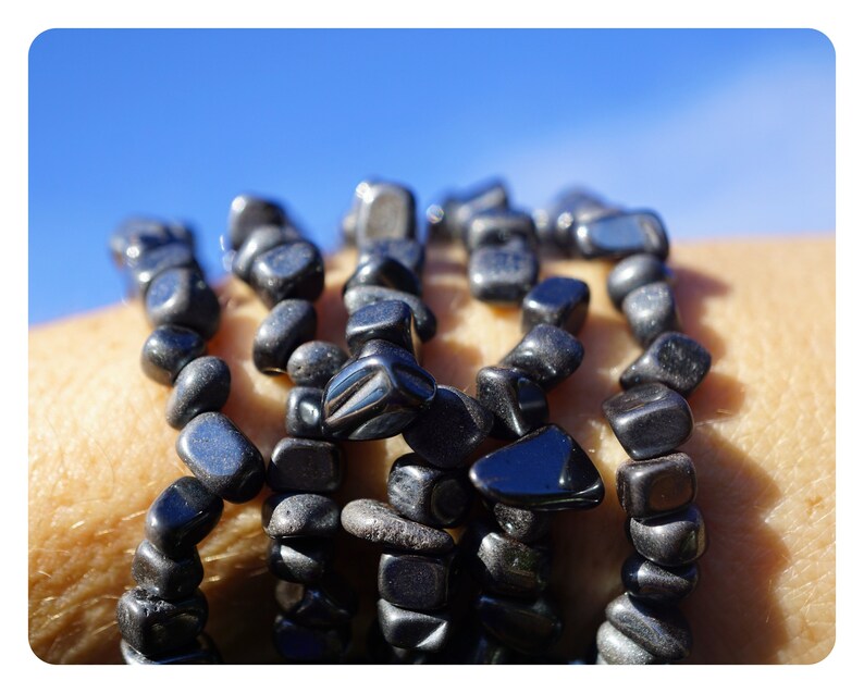 Puede incluir: Un conjunto de pulseras de piedras preciosas negras hechas con cuentas lisas de forma irregular. Las pulseras se llevan en la mu&ntilde;eca.