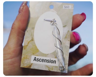 May include: A silver wire wrapped around a clear glass tube filled with white crystals. The tube is hanging from a silver loop. The tag reads "Ascension" and "$60".
