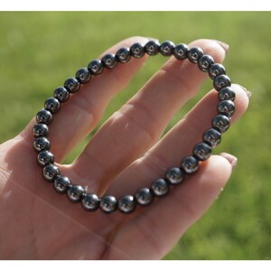 Puede incluir: Un brazalete negro hecho de cuentas redondas, lisas y brillantes de hematites.
