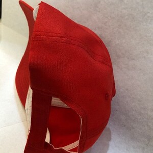 Puede incluir: Una gorra de b&eacute;isbol roja con una correa ajustable blanca en la parte posterior. La gorra est&aacute; hecha de un tejido de algod&oacute;n suave.