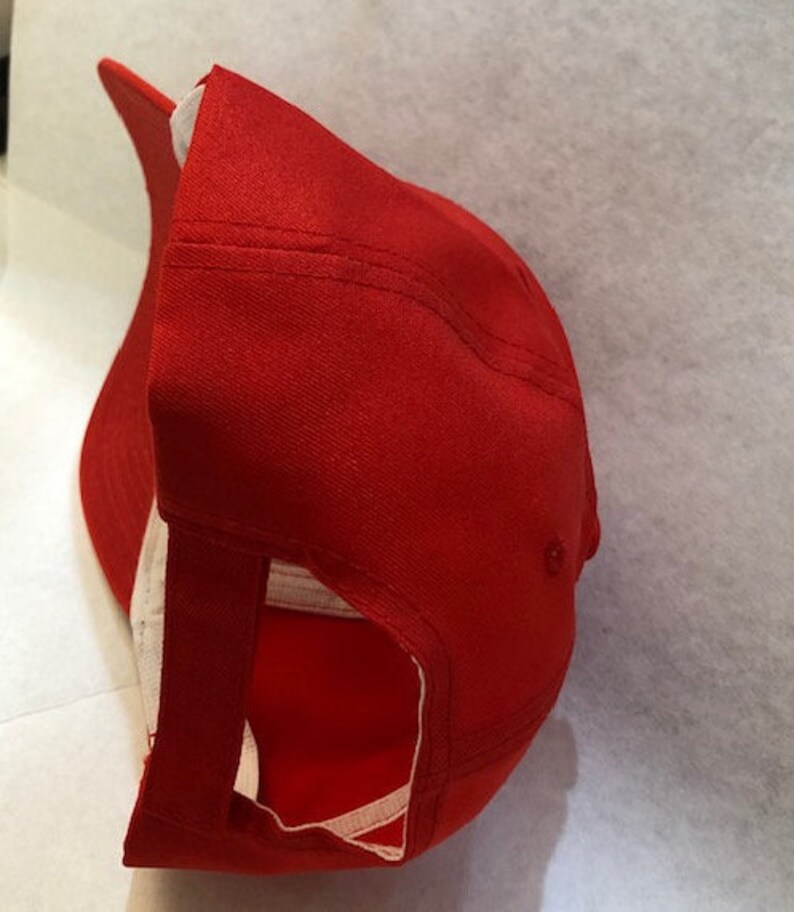 Puede incluir: Una gorra de b&eacute;isbol roja con una correa ajustable blanca en la parte posterior. La gorra est&aacute; hecha de un tejido de algod&oacute;n suave.