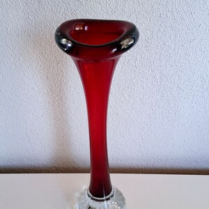 Peut inclure: Un vase en verre rouge et haut avec une ouverture &eacute;vas&eacute;e et un pied clair textur&eacute;. Le pied porte une petite &eacute;tiquette indiquant "Aalto 1962".