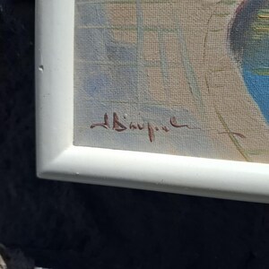 May include: A framed painting featuring a light beige background with a grid of thin, pale blue lines. A dark blue, circular shape is visible on the right side. A brown, handwritten signature is located in the lower left corner of the canvas.