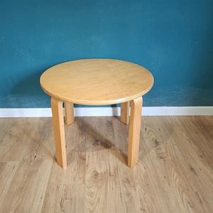 Peut inclure: Petite table ronde en bois clair. Le dessus est circulaire et repose sur quatre pieds droits. La table mesure environ 46 cm de diamètre et 41 cm de hauteur.