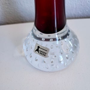 Peut inclure: Un vase en verre transparent avec une base textur&eacute;e et bull&eacute;e et un haut de couleur rouge fonc&eacute;. Le vase a un autocollant sur la base qui indique "Sweden Seda".