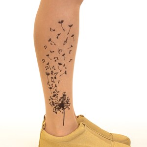 May include: A pair of tan suede shoes with a black dandelion design on the leg. The dandelion has musical notes blowing off of it.