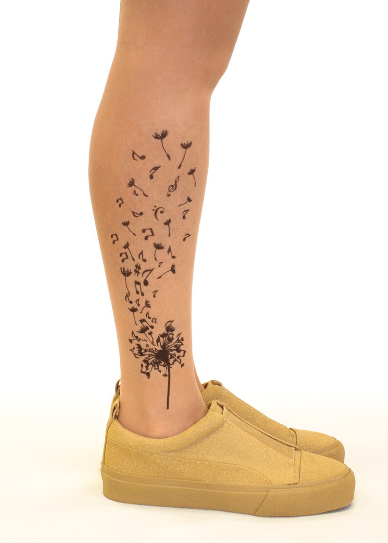 May include: A pair of tan suede shoes with a black dandelion design on the leg. The dandelion has musical notes blowing off of it.