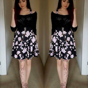 Puede incluir: Una mujer con un top negro de hombros descubiertos con un cintur&oacute;n negro, una falda floral negra y blanca y zapatos negros. Lleva medias con estampado floral.