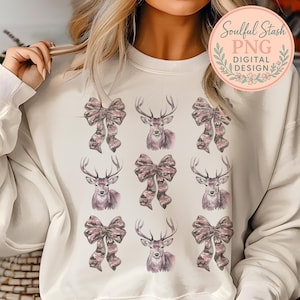 May include: A cream-colored crewneck sweatshirt featuring a repeating grid pattern of watercolor-style illustrations. The design consists of alternating images of deer heads with antlers and decorative bows, all rendered in muted shades of pink and brown.