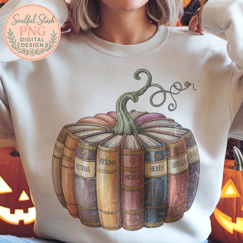 A person wearing a white sweatshirt with a graphic design of a pumpkin containing various colored books, including "POTIONS", "HEXES", "SPELLS", and "HELLS".