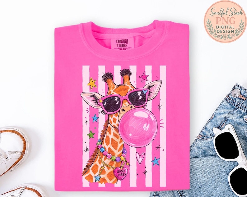 A pink t-shirt with a giraffe wearing sunglasses and a bubble gum bubble, surrounded by colorful stars and hearts.