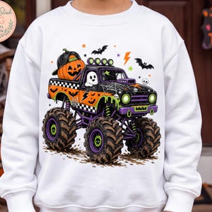 A white sweatshirt with a Halloween-themed graphic design depicting a monster truck with a jack-o-lantern on the back.