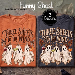May include: Two t-shirts, one orange and one dark grey, each featuring a graphic of three ghosts hanging on a clothesline with the text Three Sheets To The Wind. The ghosts hold various drinks, and the design includes plaid bows.