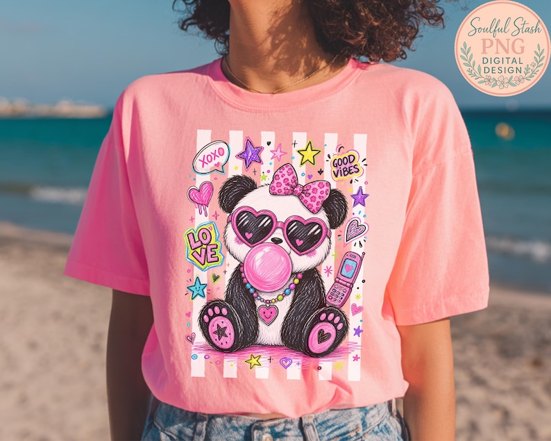 A woman wearing a pink t-shirt with a colorful graphic of a panda wearing sunglasses and a bow, surrounded by various decorative elements.