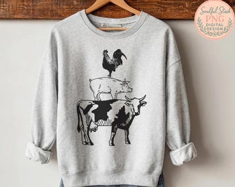 May include: A light gray sweatshirt featuring a black and white illustration of a cow, pig, and rooster stacked on top of each other. The sweatshirt has long sleeves and a crew neck.