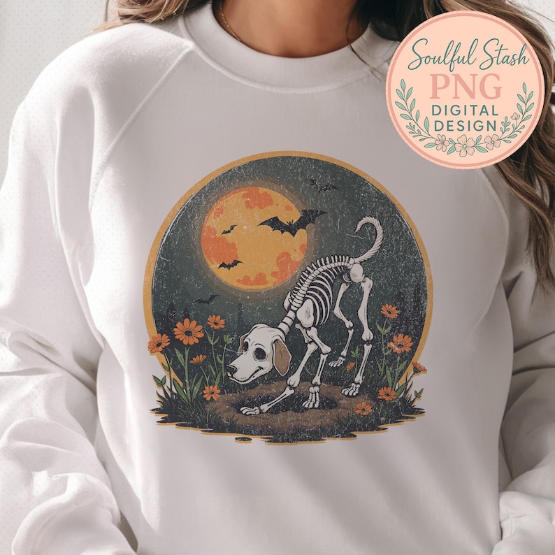 May include: White sweatshirt featuring a Halloween-themed graphic. The design includes a dog skeleton, a full orange moon, bats, and orange flowers. The text "Soulful Stash PNG DIGITAL DESIGN" is in a circular logo.
