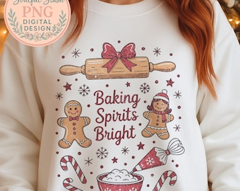 May include: White sweatshirt with a festive design featuring a rolling pin, gingerbread people, snowflakes, and candy canes. The phrase "Baking Spirits Bright" is prominently displayed. The design includes a red bow and a bowl of ingredients.