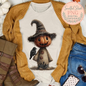 May include: A cream-colored t-shirt featuring a pumpkin-headed scarecrow with a black crow. The scarecrow wears a brown hat and a burlap outfit with button details. The text "Soulful Stash PNG Digital Design" is in a pink circle.