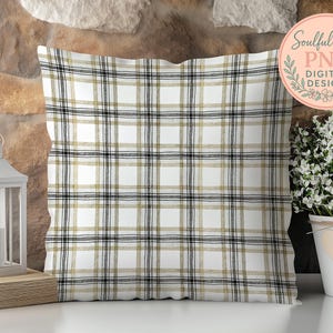a decorative pillow with a plaid pattern, placed on a wooden surface next to a potted plant and a lantern.