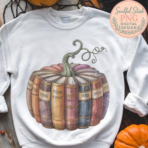 A white sweatshirt with a graphic design depicting a pumpkin with the titles "POTIONS", "HEXES", "SPELLS" written on it, surrounded by a collection of colorful books.