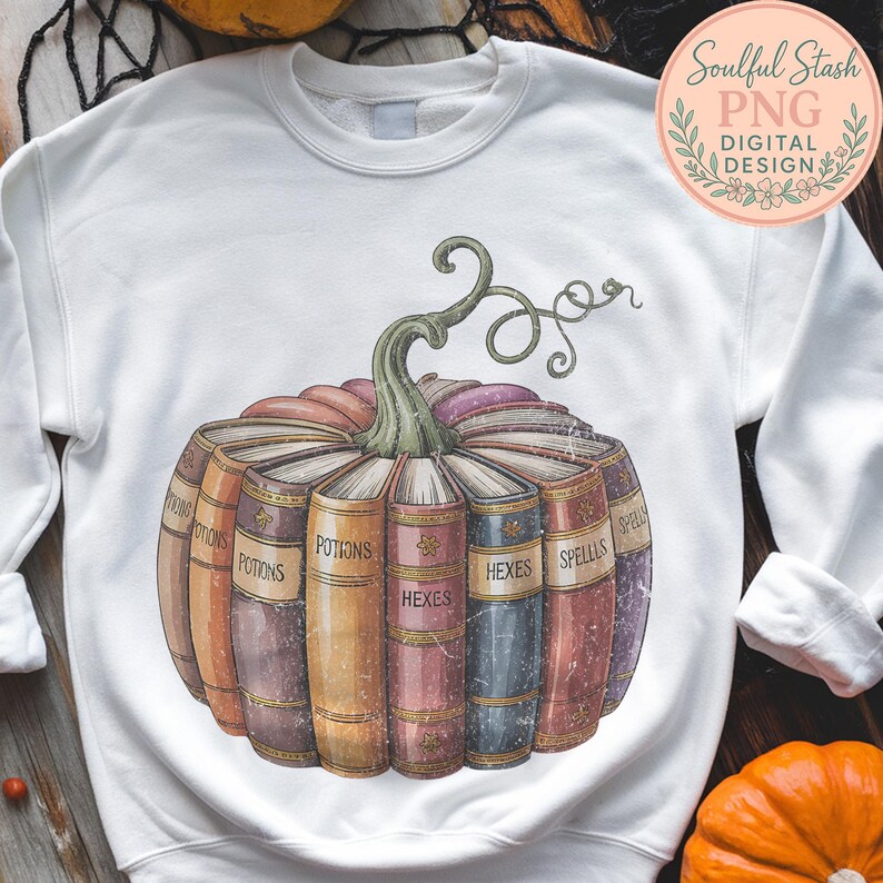 A white sweatshirt with a graphic design depicting a pumpkin with the titles "POTIONS", "HEXES", "SPELLS" written on it, surrounded by a collection of colorful books.