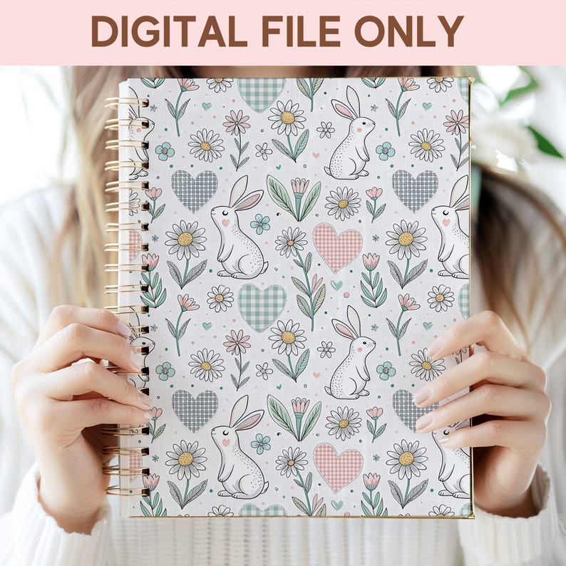 A person is holding a spiral-bound notebook with a floral and rabbit pattern printed on it.