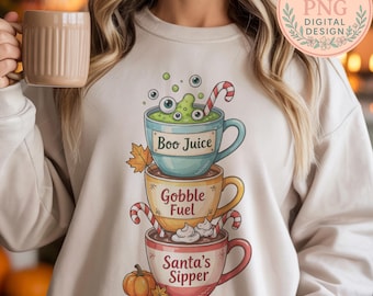 May include: Beige sweatshirt with a stacked design of three coffee cups. The top cup says "Boo Juice" with green liquid and eyeballs. The middle cup says "Gobble Fuel", and the bottom cup says "Santa's Sipper" with a pumpkin graphic.