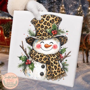 May include: A square canvas print featuring a white snowman illustration wearing a leopard print top hat and matching scarf. The snowman has a carrot nose, rosy cheeks, and is decorated with green holly leaves, red berries, and pine branches.